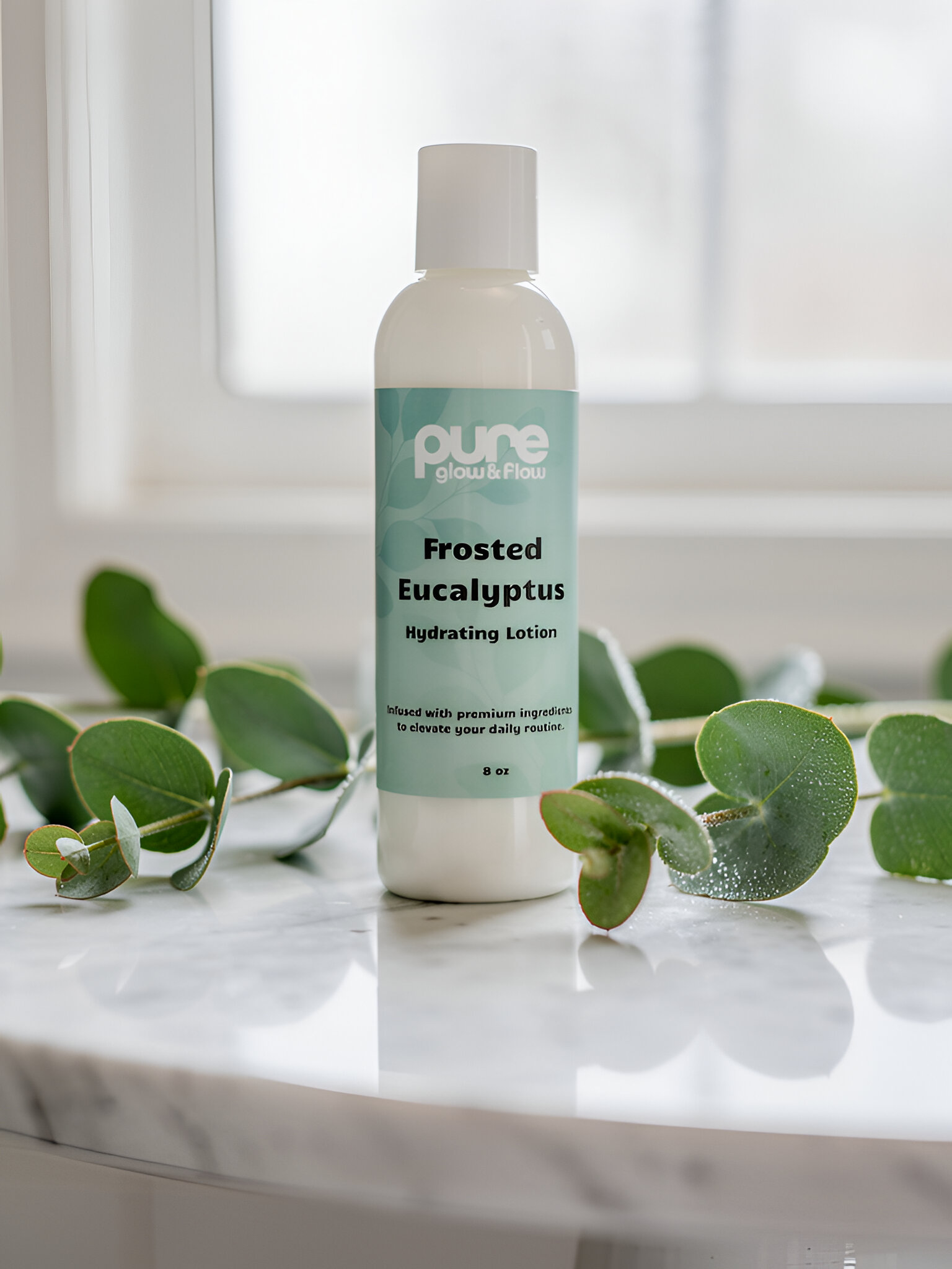 Pure Glow and Flow's Frosted Eucalyptus hydrating lotion bottle on a marble surface with eucalyptus leaves.
